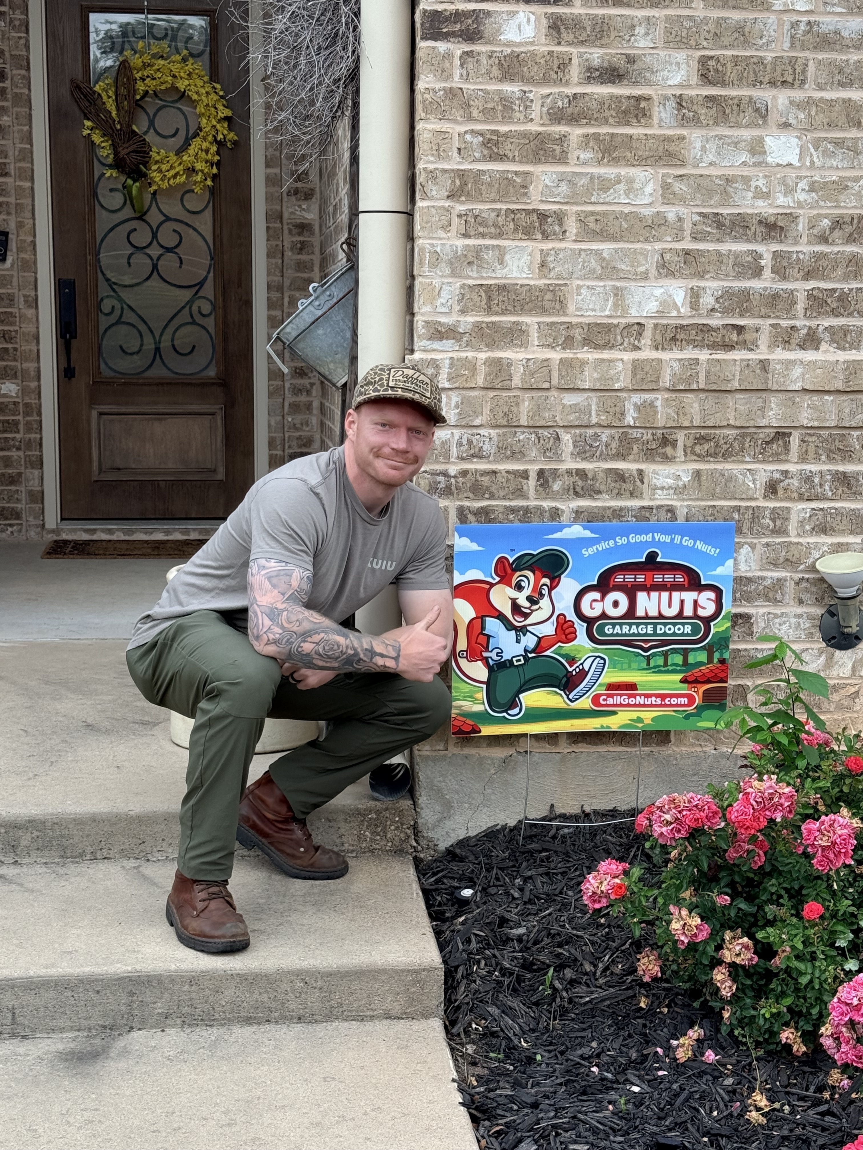 Go Nuts Garage Door technician with a yard sign after completing a job in Godley, TX